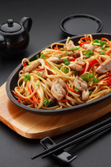 Asia food. Udon noodles with chicken on the black table.