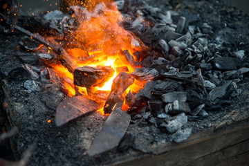 Blacksmith heats a blank for the knife in hot coals in the forge, close-up