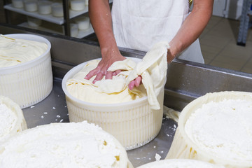 Fototapeta na wymiar Cheesemaker preparing fresh cheese to divide it into several pieces and forms