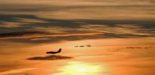 Fototapeta na wymiar Flying aircraft at sunset on a background of bright clouds