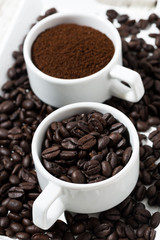 cups with ground coffee and coffee beans, vertical