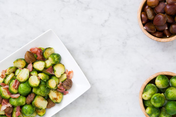 Brussels sprouts with chestnuts and bacon on white marble

