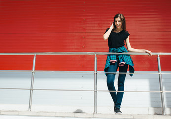 Portrait of girl in rock black style, standing outdoors in the city against the red urban wall