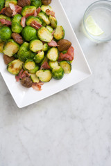 Brussels sprouts with chestnuts and bacon on white marble
