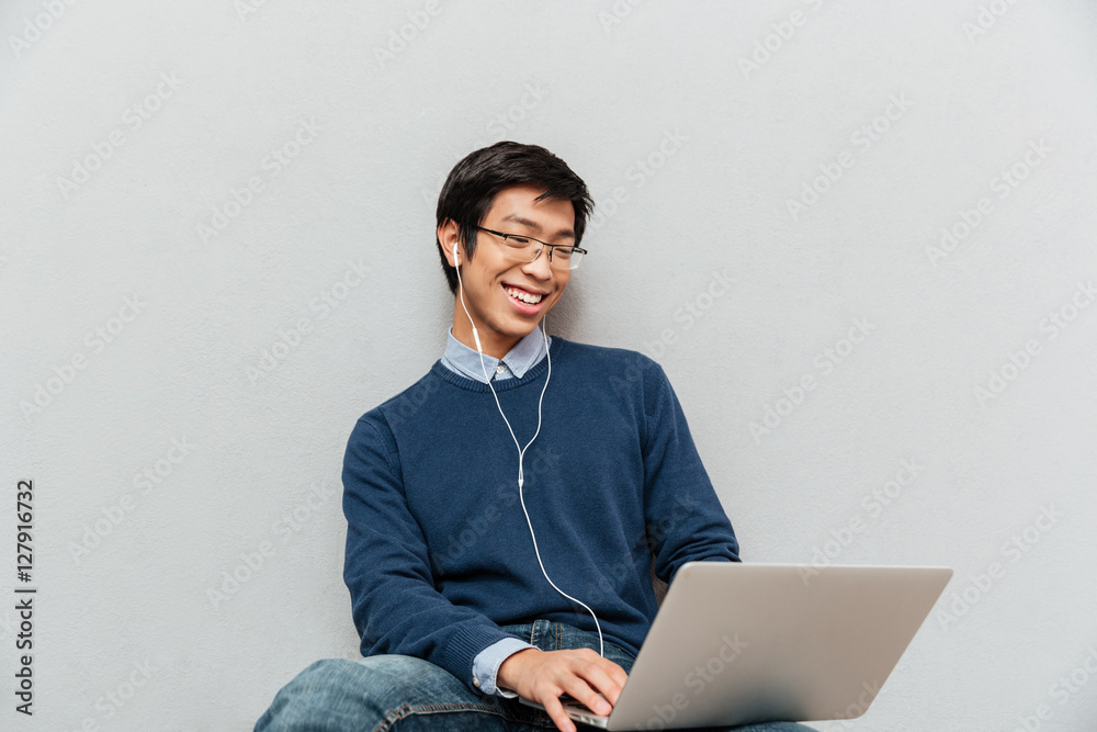 Wall mural portrait of asian man with laptop sitting on the floor