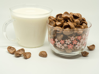 Chocolate breakfast cereal and a cap of milk.