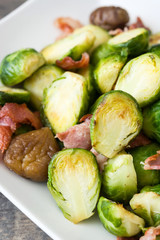 Brussels sprouts with chestnuts and bacon on wooden table
