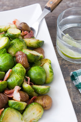 Brussels sprouts with chestnuts and bacon on wooden table
