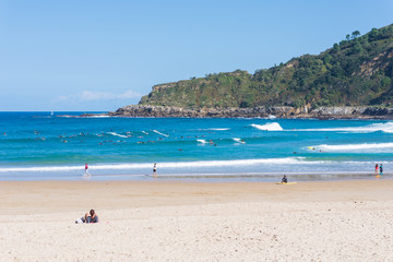 Fototapeta na wymiar Surfer do water sport, people relax at the beach La Zurriola in Donostia San Sebastian. The beach is situated at the district Gros of San Sebastian. The beach is famous for surfing,sports and relaxing