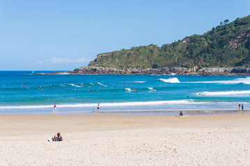 Fototapeta premium Surfer do water sport, people relax at the beach La Zurriola in Donostia San Sebastian. The beach is situated at the district Gros of San Sebastian. The beach is famous for surfing,sports and relaxing
