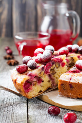Slice of homemade cranberry cake with walnuts, berries and powdered sugar on the old wooden fone. Space for text. Rustic style. Selective focus.