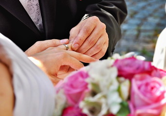 Obraz na płótnie Canvas Groom putting wedding ring on bride's finger