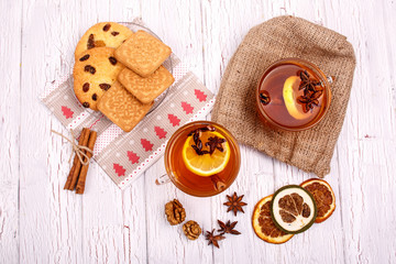 two cups of black tea,dried lemons and cinnamon sticks lying on