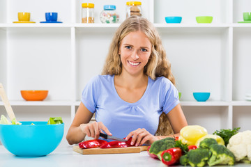 Obraz na płótnie Canvas Beautiful girl enjoys making healthy meal at her home.