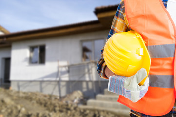 Builder with protection equipment holding hardhat