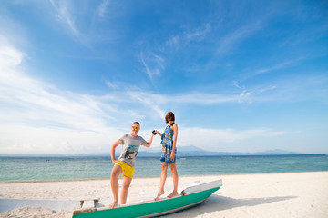 Fototapeta premium Happy young joyful couple having beach fun laughing together during summer holidays vacation on tropical beach with white sand. Beautiful energetic fresh interracial multi-ethnic couple, man and woman