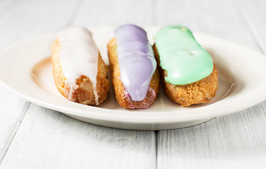 Eclairs on a white wooden background, horizontal, selective focus
