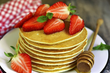 Pancakes with honey and strawberry.