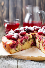 Slice of homemade cranberry cake with walnuts, berries and powdered sugar on the old wooden fone. Space for text. Rustic style. Selective focus.