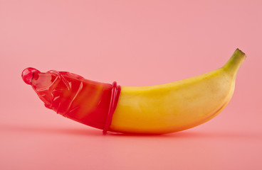 red condom and a banana - obrazy, fototapety, plakaty