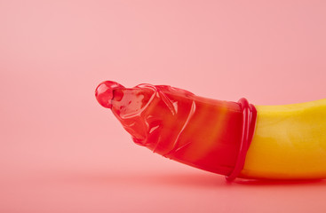 red condom and a banana - obrazy, fototapety, plakaty