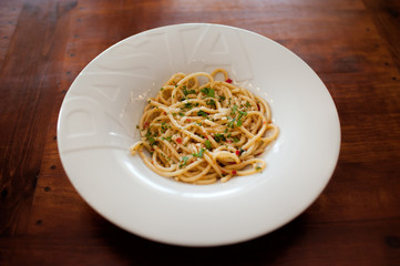 Close up view of the plate with italian styled spaghetti with parmesan, basil and dried tomatoes
