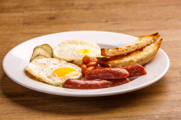 Fried eggs with bacon sausages and greens