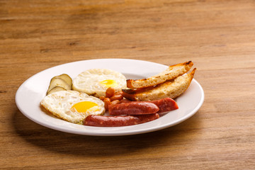 Fried eggs with bacon sausages and greens