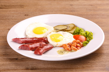 Fried eggs with bacon sausages and greens