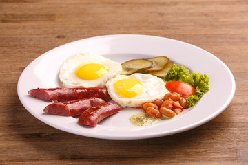 Fried eggs with bacon sausages and greens