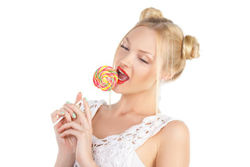 Beauty Model smiling teen girl, licking a lollipop, funny blonde hairstyle - two bumps, professional make-up. Snow-white teeth, blue eyes, long eyelashes. Isolated on white background
