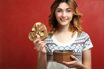 Happy girl holding in hands a gift box in the shape of a heart.