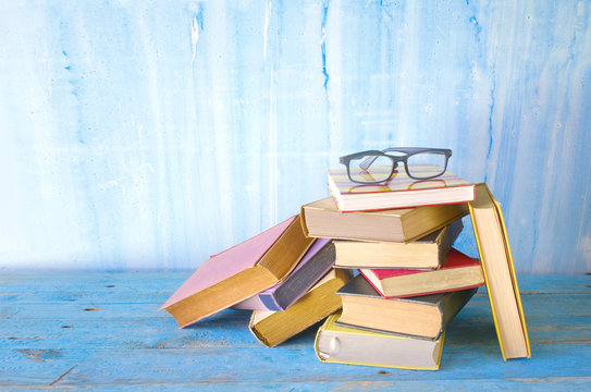 stack of old multicolored books with spectacles, grungy backgrou