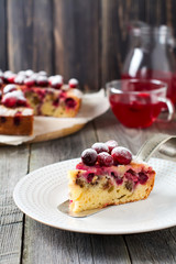 Slice of homemade cranberry cake with walnouts, berries and powdered sugar on a ceramic plate. Space for text. Rustic style. Selective focus.