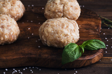 Uncooked meatballs on a dark wooden board