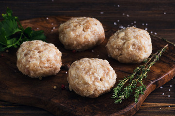 Uncooked meatballs on a dark wooden board