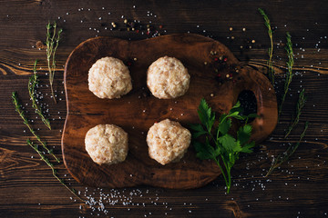 Uncooked meatballs on a dark wooden board