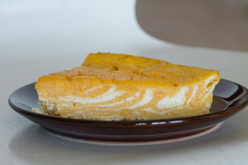 Piece of marble casserole with pumpkin and cottage cheese on plate.