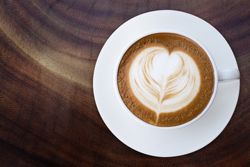 Top view of hot coffee cappuccino latte cup with saucer on wood