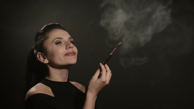 beautiful woman smokes a cigarette in a mouthpiece on a black background
