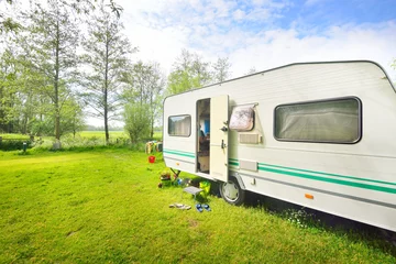 Foto op Plexiglas Caravan trailer camping on a green lawn under a tree in springtime © Aastels