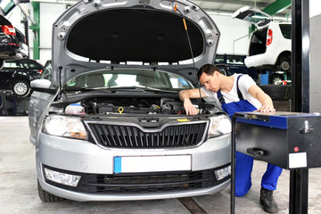 Automechaniker stellt Schweinwerfer von Fahrzeug in einer Werkstatt ein - Kundendienst Lichttest