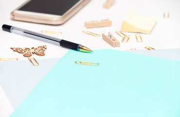 Top view of blank of paper sheet, gold stationery items, several drawing tools decorated with wooden butterfly