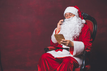 Santa Claus Christmas. Santa talking on the phone in his hand a letter, close-up