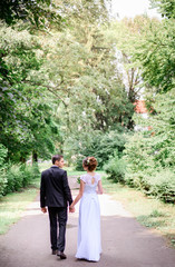 young and beautiful bride and groom standing together in the gar