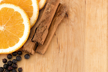 Orange slices, cinnamon sticks and juniper berries on wooden board