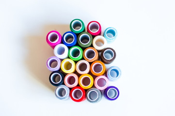 multicolored spools of thread on white background