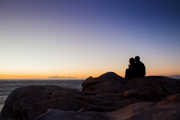 Naklejka na ściany i meble Couple sitting watching sunset