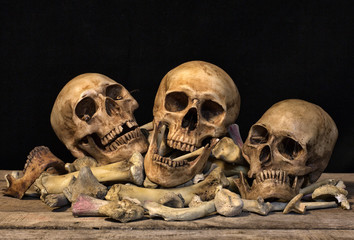 Three skull and pile of bone on old wooden plate