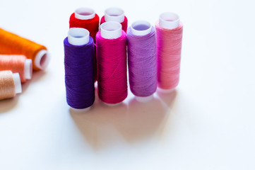 multicolored spools of thread on white background